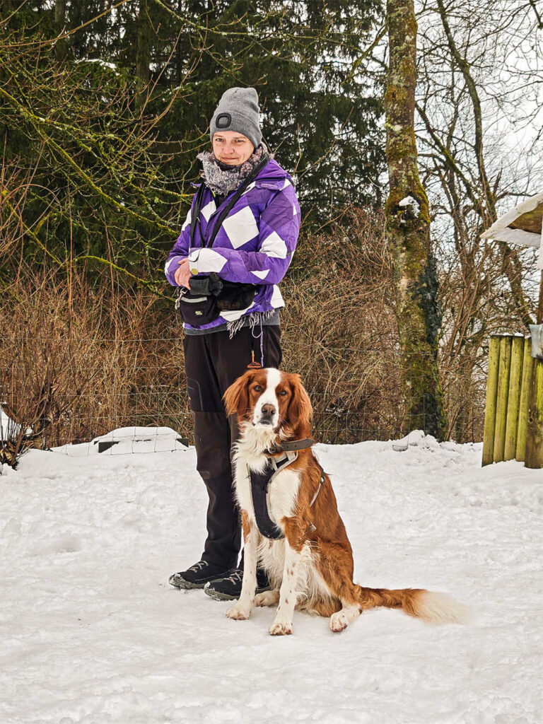 Schulhund im Training mit Halterin im Schnee