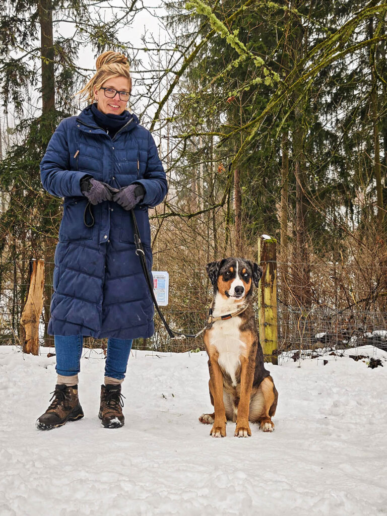 Schulhund im Training mit Halterin im Schnee